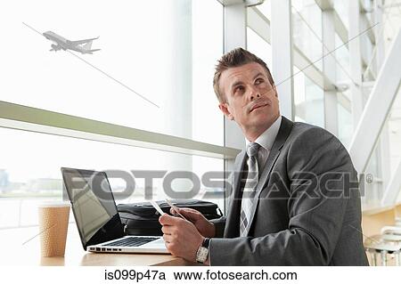 Stock Image - Businessman using laptop in airport. Fotosearch