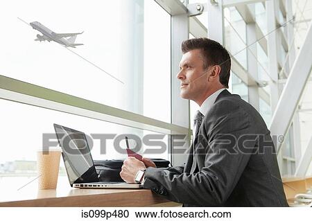 Businessman using laptop in airport View Large Photo Image Stock Image - Businessman using laptop in airport. Fotosearch