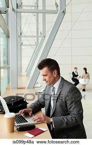 Businessman using laptop in airport View Large Photo Image Stock Image - Businessman using laptop in airport. Fotosearch