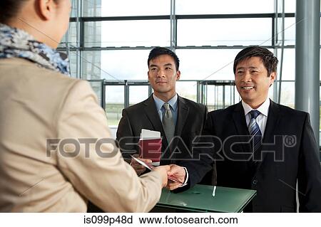 Stock Image - Businessmen checking in at airport. Fotosearch