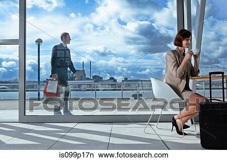 Picture - Businesswoman drinking coffee in airport. Fotosearch