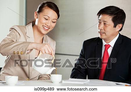 Stock Photo - Businesswoman pouring tea for businessman. Fotosearch