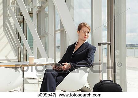 Stock Image - Businesswoman sitting in airport with digital tablet, portrait. Fotosearch
