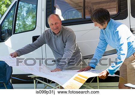Stock Image - Couple looking at map outside campervan. Fotosearch