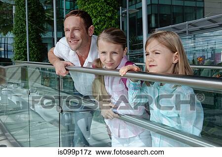 Stock Photo - Father with two daughters leaning on railing. Fotosearch
