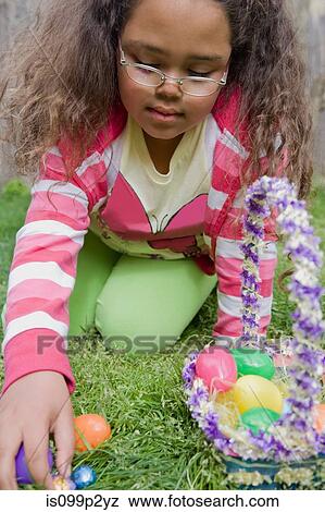 Girl finding easter eggs in grass View Large Photo Image Stock Photo - Girl finding easter eggs in grass. Fotosearch