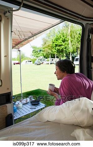 Stock Photo - Mature woman drinking hot drink in camper van. Fotosearch