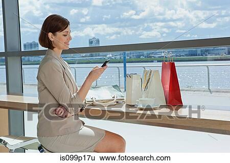 Mid adult woman texting in airport View Large Photo Image Stock Photograph - Mid adult woman texting in airport. Fotosearch