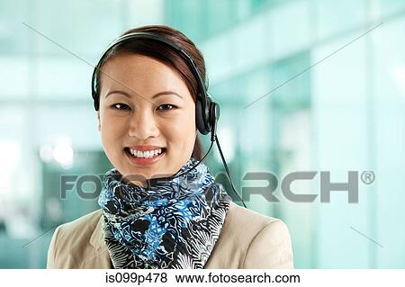 Stock Photo - Office worker wearing headset, portrait. Fotosearch