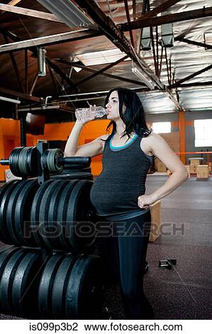 Pregnant young woman drinking mineral water View Large Photo Image Stock Image - Pregnant young woman drinking mineral water. Fotosearch