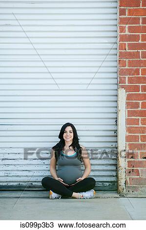 Pregnant young woman sitting cross legged, portrait View Large Photo Image Stock Image - Pregnant young woman sitting cross legged, portrait. Fotosearch