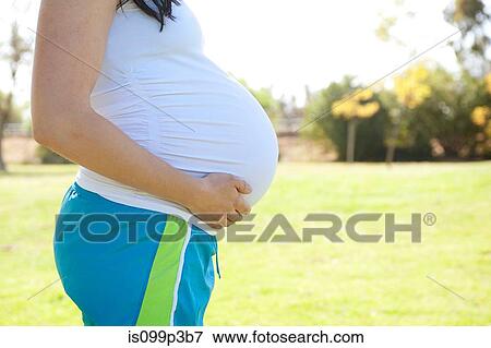 Pregnant young woman touching stomach, side view View Large Photo Image Stock Photo - Pregnant young woman touching stomach, side view. Fotosearch