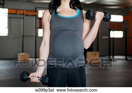 Stock Photograph - Pregnant young woman with hand weights. Fotosearch