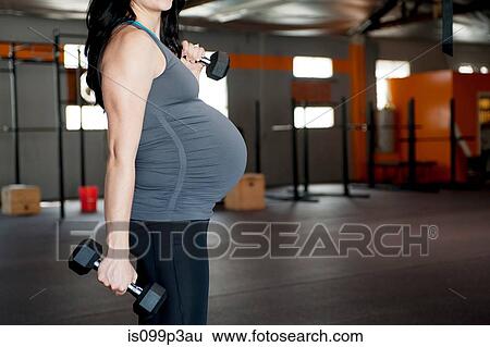 Stock Photograph - Pregnant young woman with hand weights. Fotosearch