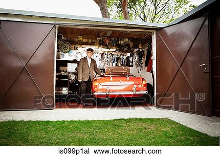 Stock Image - Senior man with vintage car in garage. Fotosearch