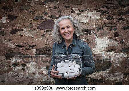 Stock Photograph - Senior woman with basket of eggs. Fotosearch