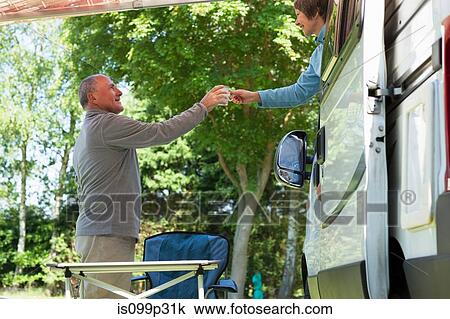 Woman offering man mug outside campervan View Large Photo Image Stock Image - Woman offering man mug outside campervan. Fotosearch