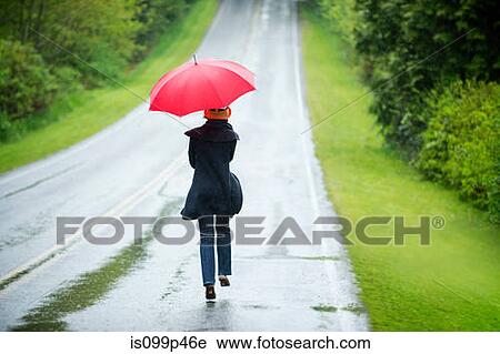 Stock Image - Woman on empty road with red umbrella. Fotosearch