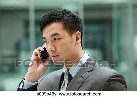 Stock Photo - Young businessman on cell phone, portrait. Fotosearch