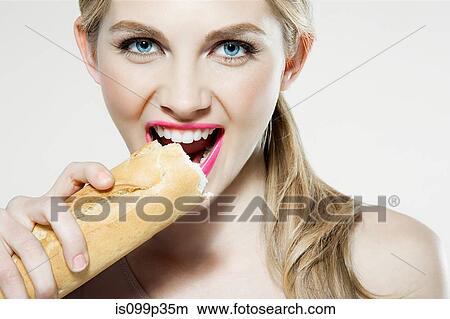 Picture - Young woman biting baguette. Fotosearch