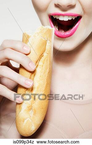 Stock Photo - Young woman biting baguette. Fotosearch
