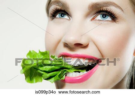 Picture - Young woman biting lettuce. Fotosearch