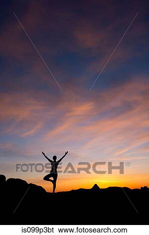 Stock Photograph - Young woman doing yoga in desert, silhouette. Fotosearch