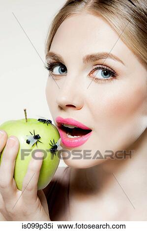 Young woman eating apple with flies on it View Large Photo Image Stock Image - Young woman eating apple with flies on it. Fotosearch