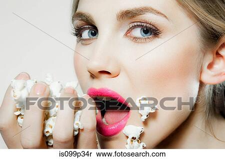 Stock Photography - Young woman eating popcorn. Fotosearch