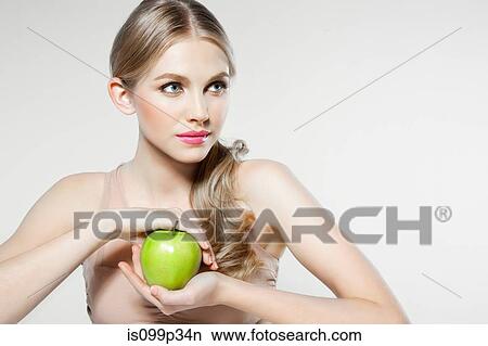 Picture - Young woman holding apple. Fotosearch