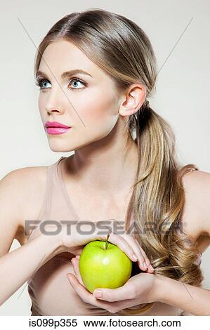 Stock Photography - Young woman holding apple. Fotosearch