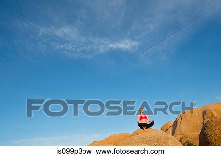 Young woman sitting on desert rocks meditating View Large Photo Image Stock Photo - Young woman sitting on desert rocks meditating. Fotosearch