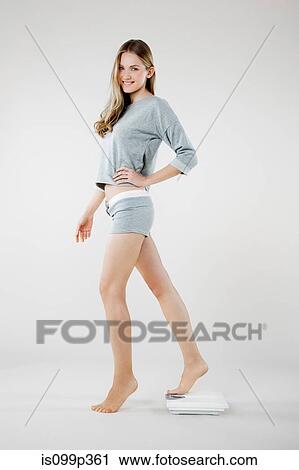 Young woman standing on weight scales View Large Photo Image Stock Image - Young woman standing on weight scales. Fotosearch