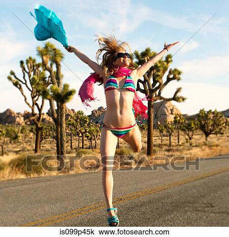 Young woman wearing bikini with arms out on desert road View Large Photo Image Stock Image - Young woman wearing bikini with arms out on desert road. Fotosearch