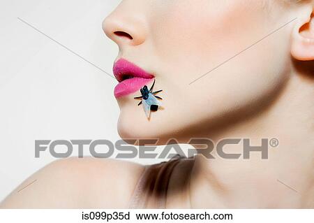 Stock Image - Young woman with plastic fly on face. Fotosearch