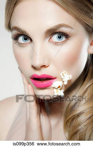 Young woman with popcorn stuck to her face View Large Photo Image Stock Photograph - Young woman with popcorn stuck to her face. Fotosearch