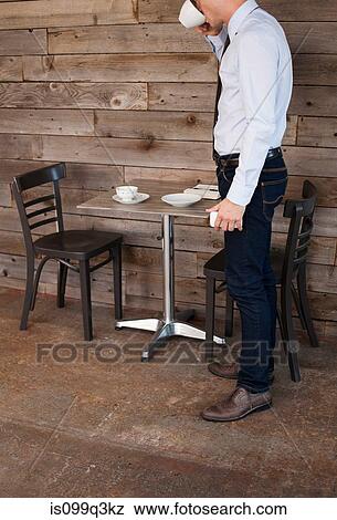 Stock Photo - Businessman finishing drink in cafe. Fotosearch