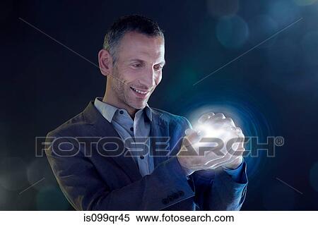 Stock Photography - Businessman holding a ball of light. Fotosearch