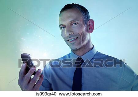 Stock Image - Businessman holding cellphone with lights. Fotosearch