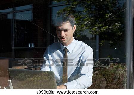 Stock Image - Businessman in cafe, view through window. Fotosearch