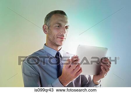 Stock Image - Businessman using digital tablet with lights. Fotosearch