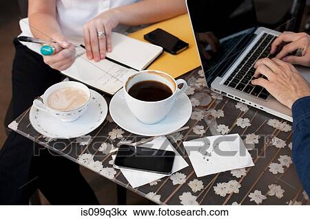 Businesspeople in cafe, man using laptop woman writing View Large Photo Image Stock Photo - Businesspeople in cafe, man using laptop woman writing. Fotosearch