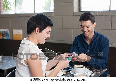 Stock Photo - Businesspeople using smartphones in cafe. Fotosearch