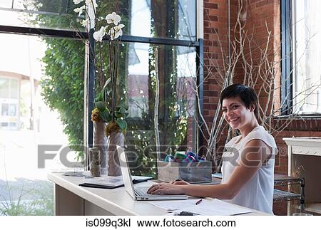 Stock Image - Businesswoman at desk using laptop. Fotosearch