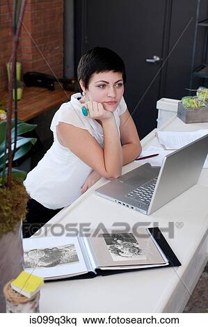 Businesswoman at desk with hand on chin View Large Photo Image Stock Photography - Businesswoman at desk with hand on chin. Fotosearch