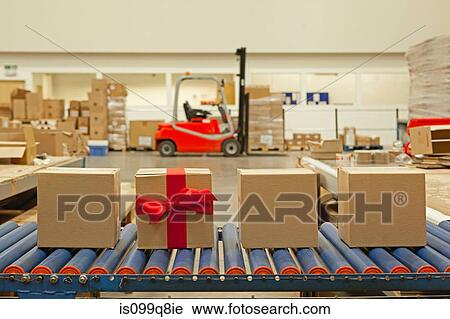 Stock Image - Cardboard box with red bow on conveyor belt. Fotosearch