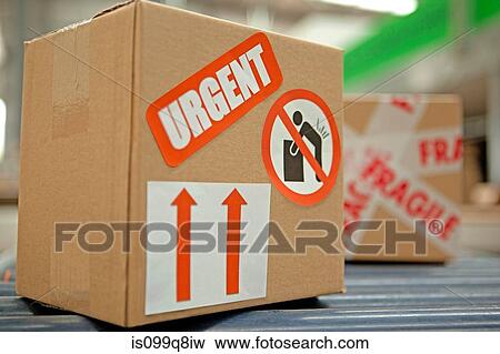 Stock Photo - Cardboard box with warning stickers on conveyor belt. Fotosearch