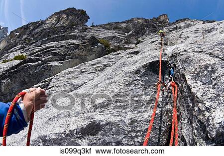 Stock Image - Climber belaying rock wall, Mount Berge, Cascade Range, Washington, USA. Fotosearch
