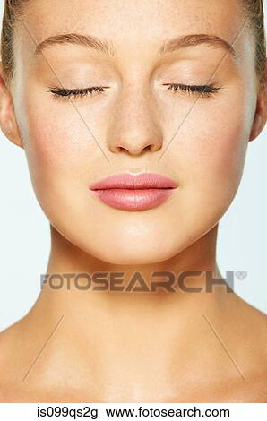 Stock Image - Close up on face of young woman with eyes closed. Fotosearch
