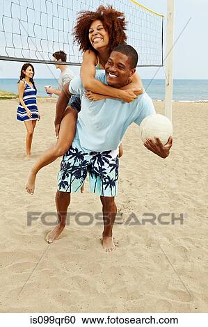 Couple on beach with volleyball, man giving woman piggyback View Large Photo Image Stock Image - Couple on beach with volleyball, man giving woman piggyback. Fotosearch
